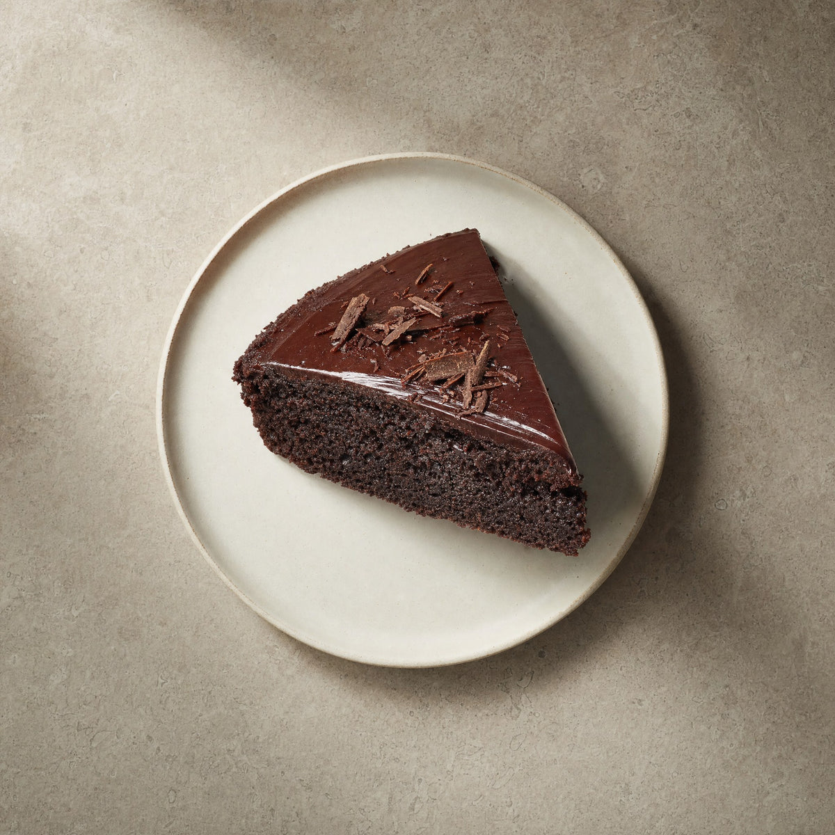 Deep chocolate protein cake slice on an off-white stoneware plate