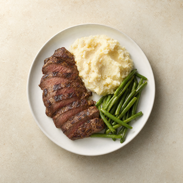 Sliced sirloin steak with mashed potatoes and green beans