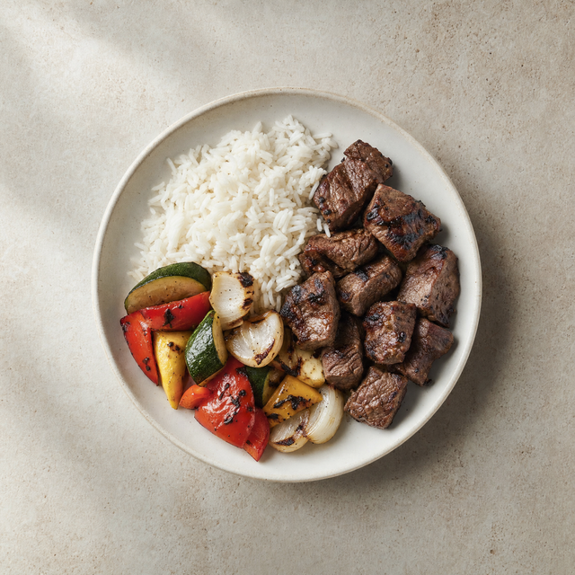Grilled beef skewers with rice, onion and vegetables
